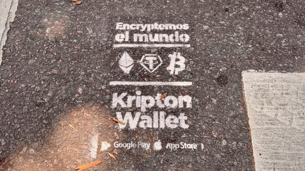 柏油路面上用白色噴漆噴的廣告:Encryptemos el mundo,下方是以太坊、Tether、比特幣的圖示與 Kripton Wallet 字樣,以及 Google Play、App Store 標誌